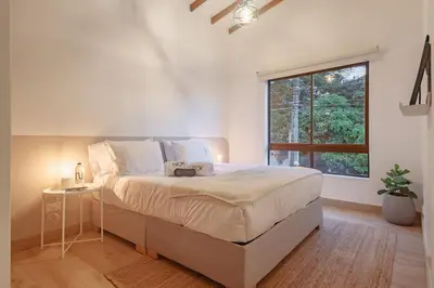 a white bedroom with a large bed and a window at NOK Peaceful 3BR in Medellin in Medellín