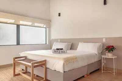 a white bedroom with a large bed with a table at NOK Peaceful 3BR in Medellin in Medellín