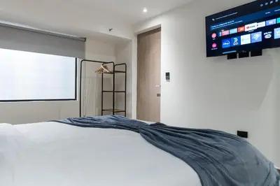 a bedroom with a white bed and a flat screen tv at Fresco Living in Medellín