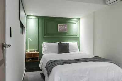 a bedroom with a green headboard and a white bed at Fresco Living in Medellín