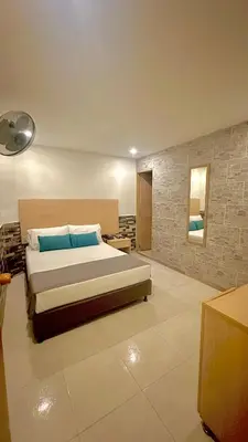 a bedroom with a large bed and a stone wall at Hotel MOVA in Medellín