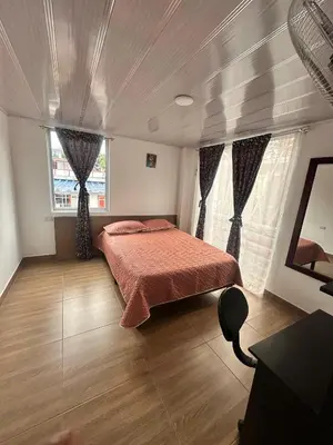 a bedroom with a bed and two windows at La Casa de Oliva in Norcasia