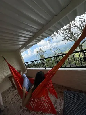 a girl laying in a hammock on a balcony at Hotel Boutique El Paisaje in Santa Bárbara
