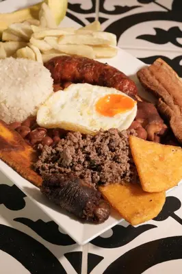 a plate of food with meat and beans and eggs at Hotel Boutique El Paisaje in Santa Bárbara