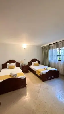 a bedroom with two beds and a window at Hotel Balcones De Malibu in Medellín