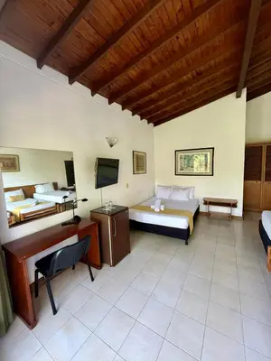 a bedroom with two beds and a desk and a television at Hotel Balcones De Malibu in Medellín
