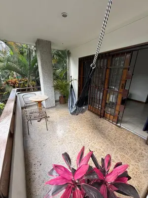 a porch with a hammock and some pink flowers at Hotel Balcones De Malibu in Medellín