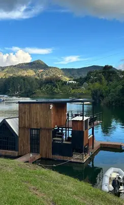 a wooden dock with a boat on the water at Cabaña flotante con jacuzzi in Guatapé