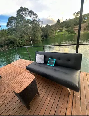a black couch sitting on a deck next to a body of water at Cabaña flotante con jacuzzi in Guatapé