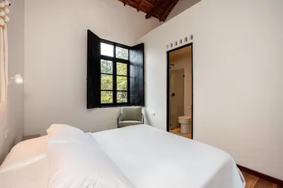 a white bedroom with a bed and a window at Hotel Boutique Casamía in Medellín