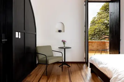 a bedroom with a bed and a chair and a window at Hotel Boutique Casamía in Medellín