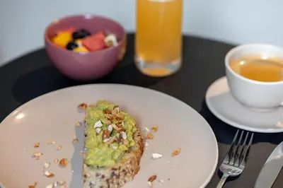 a white plate with a piece of food and a bowl of fruit at Hotel Boutique Casamía in Medellín