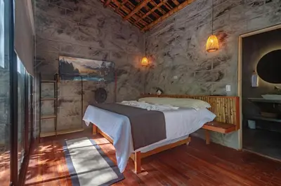 a bedroom with a bed and a stone wall at Cabaña El Bosque - En medio del bosque - Jacuzzi Privado con Calefacción y Malla Catamarán - Cerca a Medellin in Sopetran