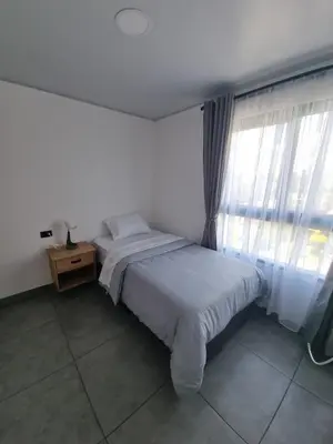 a white bedroom with a bed and a window at Andes Coliving in Estación El Salto