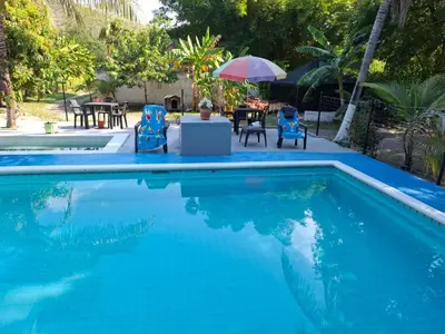 a swimming pool with chairs and a table and an umbrella at Siboney family in Honda