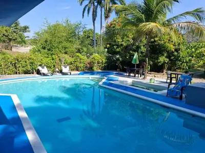 a swimming pool with blue water and palm trees at Siboney family in Honda