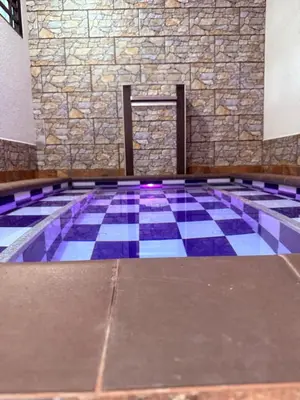a swimming pool with a tile floor and a stone wall at Casa encanto, jacuzzi privado & wifi in Mariquita