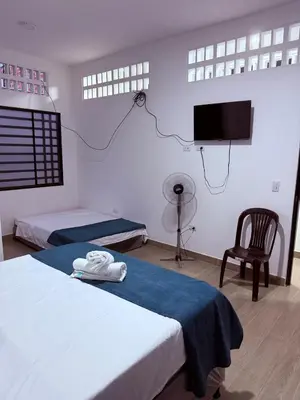 a room with two beds and a tv and a chair at Casa encanto, jacuzzi privado & wifi in Mariquita