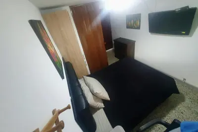 a small bedroom with a black bed with a television at Apartaestudio en laureles la castellana in Medellín