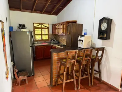 a kitchen with a counter with chairs and a refrigerator at El Paraíso Tropical in La Pradera