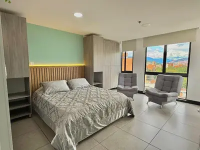 a bedroom with a bed and two chairs at Cozy Studio 703 Heart of Laureles in Medellín