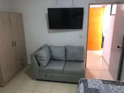 a living room with a couch and a flat screen tv at Individual studio apartment 2 in Medellín