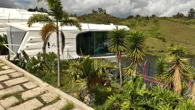a white rv parked next to some palm trees at Roka Hotel in Guatapé