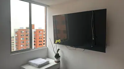 a television on a wall in a room with a window at Espectacular Habitacion Privada en Apartamento in Medellín