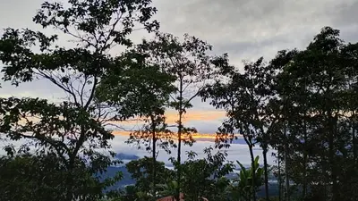 a sunset over a body of water with trees at Rural Cabin Among Clouds in Támesis