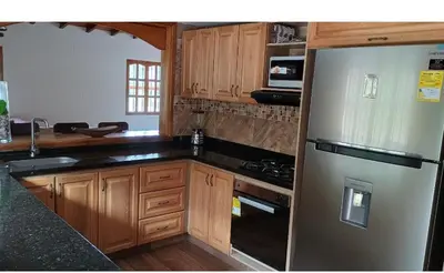 a kitchen with a stainless steel refrigerator and wooden cabinets at Villa marinilla in Santuario