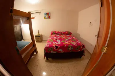 a bedroom with a bed with a red comforter at Acogedora casa Refugio del Altisimo in Medellín