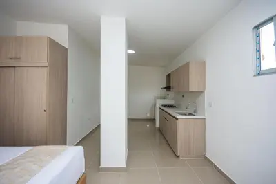 a bedroom with a bed and a kitchen in a room at Apartahotel Ces in Medellín