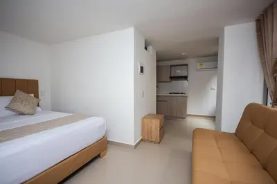 a bedroom with a bed and a couch and a kitchen at Apartahotel Ces in Medellín