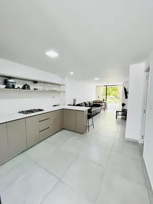 a white kitchen with a counter and a living room at Central apartment in Bello in Bello