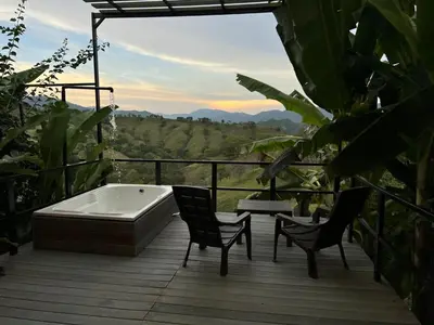a bath tub sitting on a deck with two chairs at Cabañas Flor Del Monte in Sopetran