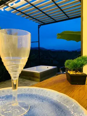 a wine glass sitting on a table in front of a tub at Cabañas Flor Del Monte in Sopetran