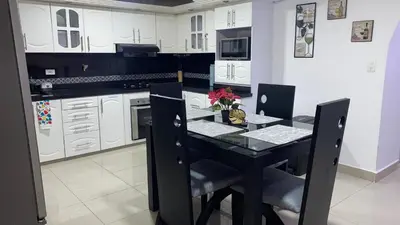 a kitchen with a black table and white cabinets at Casa Primaveral Espaciosa Cerca al Estadio in Medellín