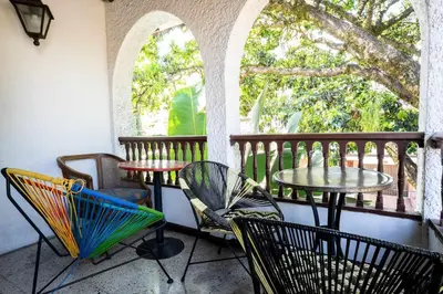 a balcony with chairs and tables and a table with umbrella at Bright Colonial 5BR House with Balcony in Medellín
