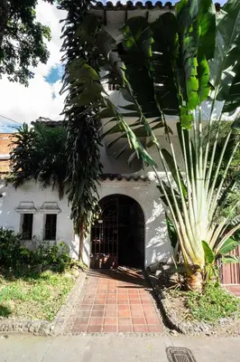 a house with a palm tree in front of it at Bright Colonial 5BR House with Balcony in Medellín
