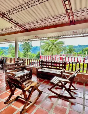 a room with chairs and tables and a balcony at Finca La Carmelita Casa Campestre con Piscina y entre Montañas a sólo minutos de Santa Rosa de Cabal in Santa Rosa de Cabal