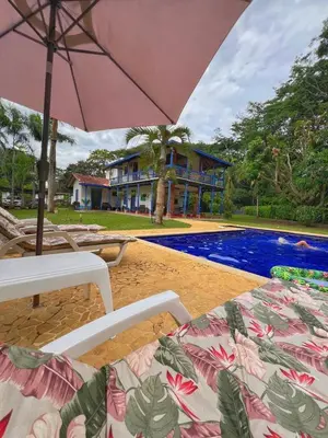 a beach with two chairs and an umbrella and a pool at San José del refugio in Jericó
