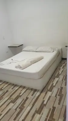a white bed sitting on top of a wooden floor at Hostal Manantiales La Esperanza in Cocorná