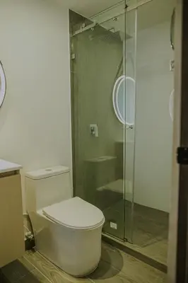 a bathroom with a toilet and a glass shower at Torre U kooliving in Manizales