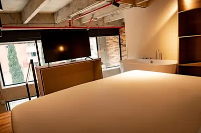 a room with a bed and a tv and a sink at Uukam by Bernalo Hotels in Medellín
