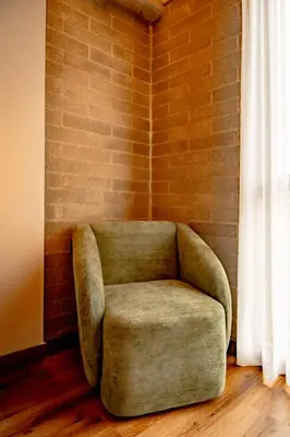 a chair sitting in a room next to a brick wall at Uukam by Bernalo Hotels in Medellín
