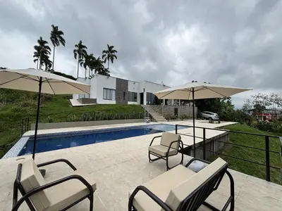 a patio with chairs and umbrellas next to a pool at Casa Campestre con Piscina in Manizales