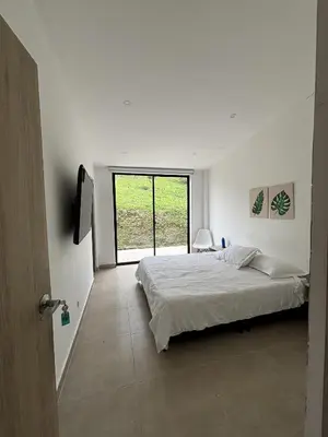 a white bedroom with a bed and a window at Casa Campestre con Piscina in Manizales