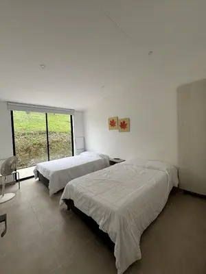 two beds in a white room with a window at Casa Campestre con Piscina in Manizales