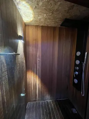 a bathroom with a shower with a wooden wall at Ikuna Luxury Glamping 1h from Medellin with Private Jacuzzi in San Vicente