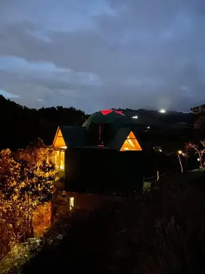 a tent on a hill at night at Ikuna Luxury Glamping 1h from Medellin with Private Jacuzzi in San Vicente